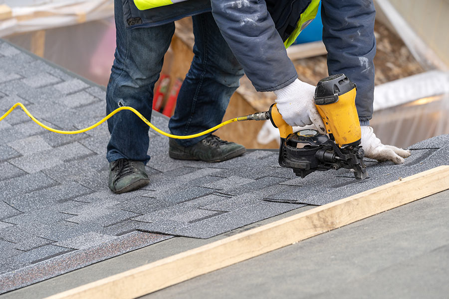 roofer installing roof tiles with nailgun